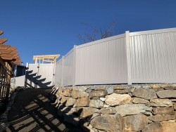 Vinyl fence on rock retaining wall